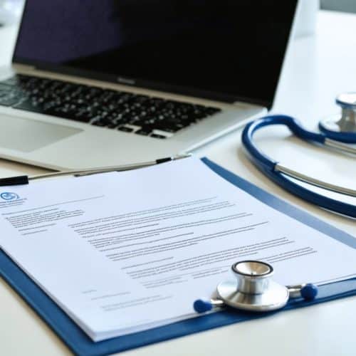 Bureau d’un professionnel de santé libéral avec ordinateur portable, courrier administratif et stéthoscope